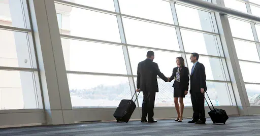 Business colleagues with luggage meeting in an airport terminal